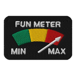 May include: Embroidered patch featuring a "FUN METER" with a green, yellow, and red gauge. A white arrow indicates the level of fun, pointing towards "MAX". The patch has a black background, and the text is white.