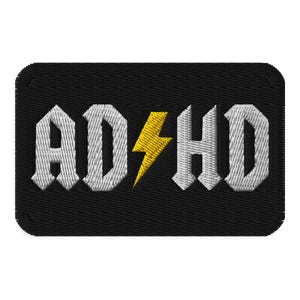 May include: Embroidered black patch with the white text "ADHD" in a gothic font, featuring a yellow lightning bolt replacing the "&" symbol. The patch has a stitched border.
