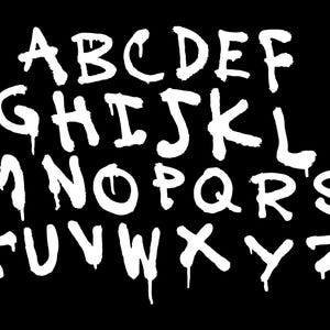 May include: White graffiti-style alphabet letters A through Z on a black background. The letters have a dripping paint effect, giving them a street art aesthetic. The image is a bold, graphic design.