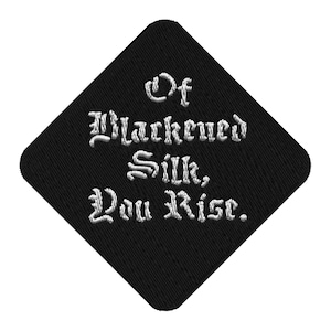 May include: A white ceramic mug with a black handle and the text "But First, Coffee" in a black, handwritten-style font. The mug is on a white surface.