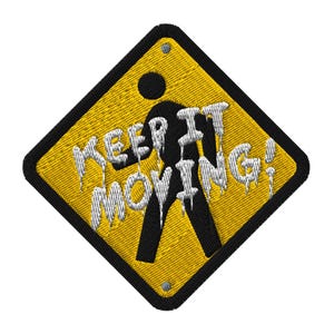 Peut inclure: Écusson brodé avec un fond jaune et une bordure noire. L'écusson présente une silhouette noire d'une personne marchant et les mots "KEEP IT MOVING!" en lettres blanches dégoulinantes. Deux petits rivets argentés sont visibles.