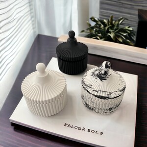 May include: Three decorative lidded jars in white, black, and marble patterns. Each jar has a ribbed design and a spherical knob on the lid. The jars are displayed on a white surface with the text "KSLODR BOLE".