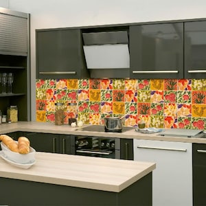 May include: Modern kitchen with dark gray cabinets, a light wood countertop, and a colorful floral tile backsplash. The kitchen includes a stove, sink, and island with a light wood surface. A loaf of bread sits in a white bowl.