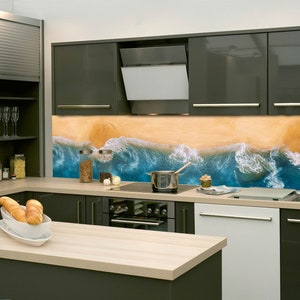 Può includere: Una cucina moderna con armadi grigi e uno schienale con una scena di spiaggia con onde blu che si infrangono su una costa sabbiosa.