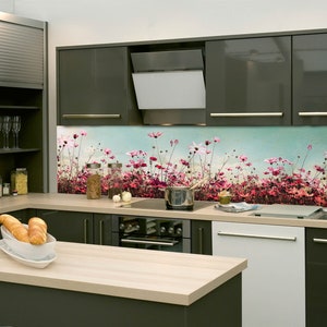 Può includere: Una cucina moderna con armadietti grigio scuro e uno schienale floreale. Lo schienale presenta un campo di fiori rosa e bianchi su uno sfondo di cielo blu. Il piano di lavoro è in legno chiaro.