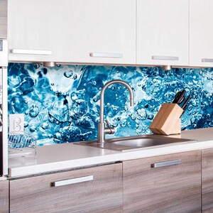 Puede incluir: Una cocina moderna con un horno de acero inoxidable y un salpicadero de agua de color azul y blanco. El salpicadero presenta un diseño de gotas de agua y burbujas. Un grifo de acero inoxidable está montado sobre un fregadero de acero inoxidable.