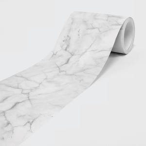 May include: A roll of adhesive contact paper featuring a white surface with a grey marble vein pattern. The material is wound around a cylindrical core, showing a smooth texture and a repeating natural stone design across the length of the paper.