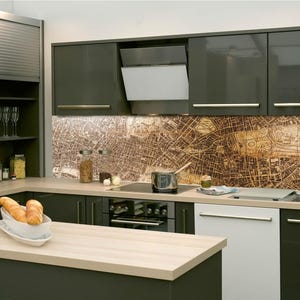 May include: Modern kitchen with dark gray cabinets, a light wood countertop, and a backsplash featuring a vintage map design. Includes a built-in oven, range hood, and a stainless steel sink. A white bowl holds bread.