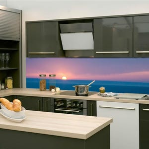 Può includere: Cucina moderna con mobili grigio scuro, un piano di lavoro in legno chiaro e un paraschizzi con una scena del tramonto. Include una cappa aspirante, un forno e un lavello in acciaio inossidabile. Una pagnotta è sul piano di lavoro.