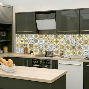 Puede incluir: Una cocina moderna con gabinetes gris oscuro y una isla con encimera de madera clara. El salpicadero presenta azulejos estampados en amarillo, azul y blanco. Electrodomésticos de acero inoxidable y lavavajillas blanco.