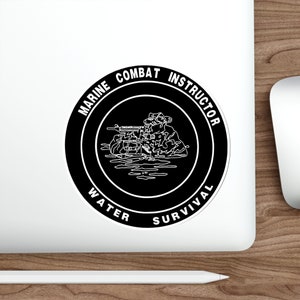 May include: Black and white sticker with a circle design. The circle has the text "Marine Combat Instructor Water Survival" around the outside. Inside the circle is a line drawing of a soldier in water with a rifle.