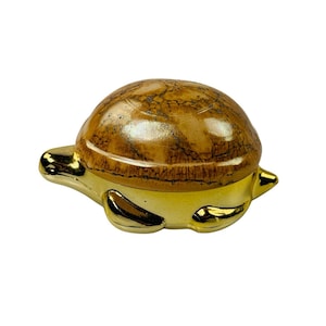 May include: A small, golden turtle figurine with a brown, marbled shell. The turtle is sitting on a white background.