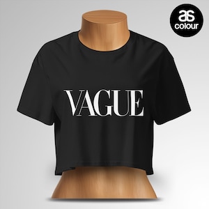 May include: Black crop top with the word "VAGUE" in white, displayed in a bold, serif font. The shirt is short-sleeved and has a round neckline. The "as colour" logo is in the upper right corner.