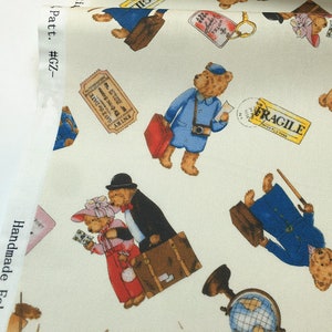 May include: White fabric with a repeating pattern of brown teddy bears wearing different outfits and carrying luggage. The bears are travelling and some are wearing hats. The fabric has the text "Pat. #GZ-" and "Handmade Fabri" on the side.