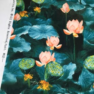 以下が含まれることがあります： 濃いティール色の背景に、蓮の花と葉の模様が描かれた生地。花はソフトピーチ色で、葉はティールと濃い緑の混合色です。生地は水彩画のような効果があります。