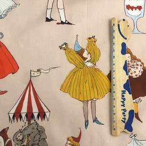 May include: A pink fabric with a repeating pattern of girls in various dresses, a circus tent, and a wooden ruler with the words "Happy Party" printed on it.