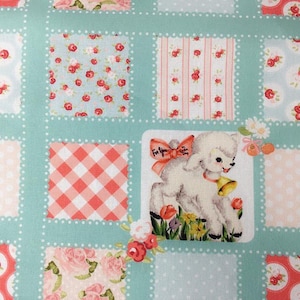 Pode incluir: Um tecido de patchwork com fundo azul claro e vários padrões em rosa, branco e vermelho. Os padrões incluem bolinhas, listras, xadrez e desenhos florais. Um pequeno cordeiro com um laço rosa é apresentado no centro do tecido.