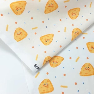 Puede incluir: Papel blanco con un patrón repetido de cuñas de queso sonrientes, puntos naranjas y confeti azul. La palabra "cheese" está impresa en naranja. El papel está doblado.
