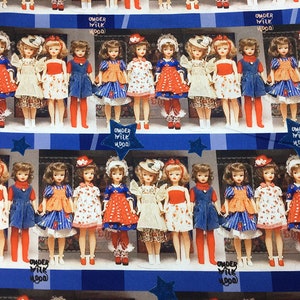 Op de afbeelding: Een vintage patroon met rijen poppen die verschillende jurken dragen met rood-wit-blauwe patronen. De poppen zijn gerangschikt in een etalage met de tekst "Under Milk Wood" die herhaald wordt.