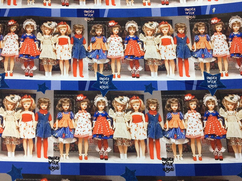 Op de afbeelding: Een vintage patroon met rijen poppen die verschillende jurken dragen met rood-wit-blauwe patronen. De poppen zijn gerangschikt in een etalage met de tekst "Under Milk Wood" die herhaald wordt.