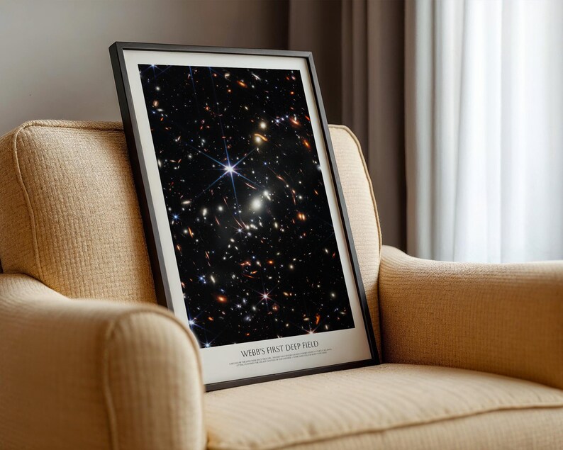 a framed photograph of a distant galaxy, with the text "WEB'S FIRST DEEP FIELD" below the image.