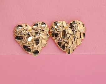 May include: A pair of gold heart-shaped earrings with a textured surface.