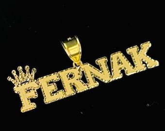 May include: Gold pendant necklace with the name "FERNAK" spelled out in block letters with a small crown above the first letter.