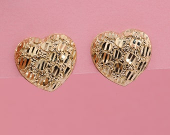 May include: A pair of gold heart-shaped earrings with a textured diamond pattern.
