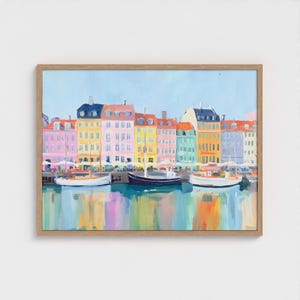 Pode incluir: Uma impressão artística emoldurada de uma paisagem urbana colorida com edifícios em tons de rosa, amarelo, verde e azul. Barcos estão atracados na água em frente aos edifícios. A água reflete as cores dos edifícios.