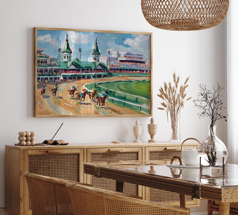 Puede incluir: Pintura enmarcada que representa una carrera de caballos. La obra presenta un hip&oacute;dromo con caballos y jinetes, gradas y un campo verde. La paleta de colores incluye tonos de marr&oacute;n, verde, azul y blanco, creando una escena vibrante.