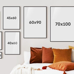 Puede incluir: Una colecci&oacute;n de impresiones art&iacute;sticas enmarcadas en varios tama&ntilde;os, incluyendo 18x13, 30x21, 30x30, 30x40, 40x50, 40x60, 45x60, 50x50, 70x50, 60x90 y 70x100 cm. Los marcos negros se exhiben en una pared clara sobre una cama con cojines naranjas y marrones.