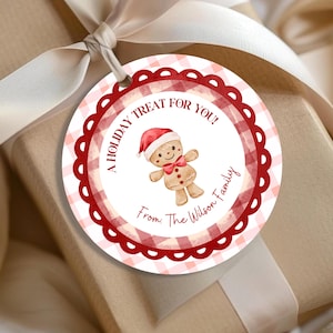 Puede incluir: Una etiqueta de regalo redonda con un borde festoneado rojo y un patrón de cuadros rojos y blancos. La etiqueta presenta un hombre de jengibre de acuarela con un gorro de Papá Noel y el texto "A Holiday Treat For You!" y "From: The Wilson Family".