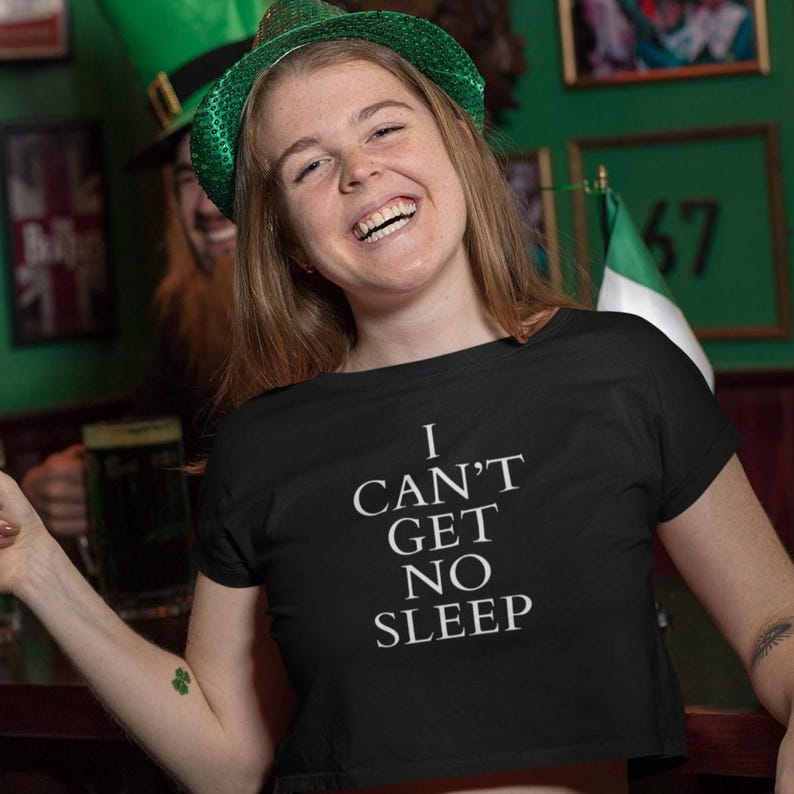 Black unisex tee with large white text saying “I Can’t Get No Sleep” on a plain background, insomnia quote tee, music‑inspired slogan top.