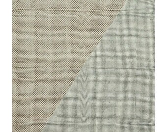 May include: A rectangular rug with a diagonal split. One half is a light brown with a textured pattern, the other half is a light blue with a woven pattern. The rug has a fringe border.