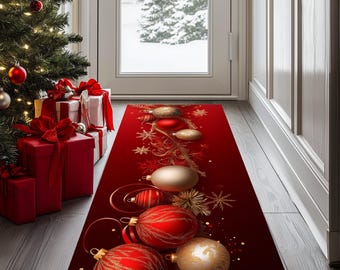 Op de afbeelding: Een feestelijk rode kerstlopermat met gouden en rode ornamenten en sneeuwvlokken. De loper is geplaatst in een deuropening, met een kerstboom en ingepakte cadeaus zichtbaar aan de linkerkant. De achtergrond toont een besneeuwde buitenscène.
