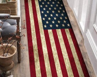 May include: A rectangular rug featuring the American flag design. The rug has a distressed look with red and white stripes and a blue field with white stars. The rug is placed on a wooden floor.