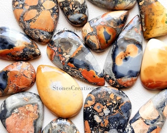 May include: A collection of 12 teardrop-shaped, polished, natural stone cabochons. The stones are a mix of brown, orange, black, and white with a mottled, marbled pattern.