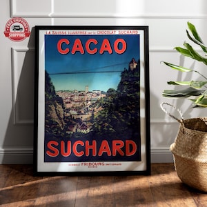 May include: A framed vintage advertisement for Suchard chocolate, featuring the text "CACAO" in red letters. The poster depicts a Swiss town with a bridge and mountains, with the words "SCHWEIZ FRIBOURG SWITZERLAND SUISSE" at the bottom.
