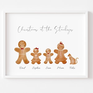 May include: A white framed print with the text "Christmas at the Stanleys" at the top.  Five gingerbread people stand in a row, with a gingerbread cat to the right.  The gingerbread people are labelled "Dad", "Sophia", "Sam", "Mum", and "Felix".