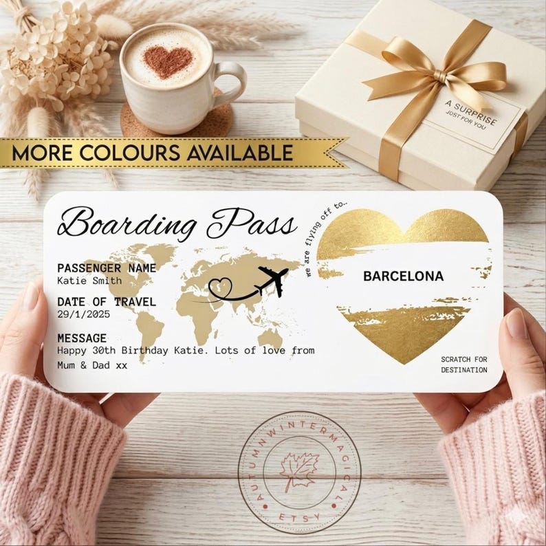 May include: A personalized boarding pass design with a gold world map and heart, the text "Barcelona", and the message "Happy 30th Birthday Katie." A coffee cup and gift box are in the background. The text "More Colors Available" is also present.