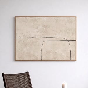 Puede incluir: Impresión artística abstracta en un marco de madera. La obra presenta un fondo beige texturizado con un diseño minimalista de líneas negras. La impresión cuelga sobre una silla y una mesa auxiliar de color marrón oscuro. El texto "CURIOSITY ES ART | HIGH QUALITY CANVAS" está en la parte inferior.