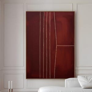 Puede incluir: Una gran pintura abstracta rectangular en tonos burdeos con líneas doradas verticales. La pintura cuelga sobre un sofá blanco y una mesa de centro redonda negra. El texto "CURIOSITY ES ART | HIGH QUALITY CANVAS" está en la parte inferior.