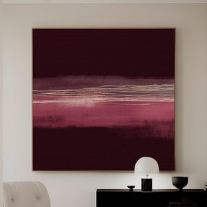Puede incluir: Gran obra de arte abstracta sobre lienzo en tonos burdeos y rosa, con pinceladas horizontales y un marco dorado. La obra cuelga sobre un mueble negro, una silla blanca y un reposapiés. El texto "CURIOSITY ES ART | HIGH QUALITY CANVAS" está en la parte inferior.