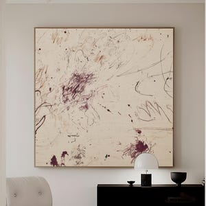 Puede incluir: Lienzo de arte abstracto con fondo crema y marcas burdeos y marrones. La obra de arte está enmarcada en un marco dorado y cuelga sobre un mueble negro. El texto "CURIOSITY ES ART | HIGH QUALITY CANVAS" está en la parte inferior.