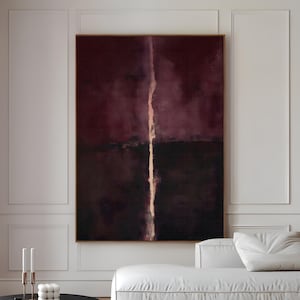May include: Large abstract canvas art with a deep burgundy and black color palette, bisected by a vertical, lighter-toned stripe. The artwork hangs above a white sofa and a black round coffee table. The text "CURIOSITY ES ART | HIGH QUALITY CANVAS" is at the bottom.