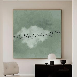 Puede incluir: Una impresión artística en lienzo enmarcada que representa una bandada de pájaros negros volando sobre una nube blanca contra un fondo verde apagado. La obra de arte se exhibe en un espacio de vida moderno. El texto "HIGH QUALITY CANVAS" es visible.