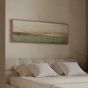 Könnte beinhalten: Ein rechteckiges Landschaftsgemälde in einem hellen Holzrahmen mit horizontalen Bändern in gedämpftem Salbeigrün, sanftem Beige und Cremetönen. Das Kunstwerk zeigt eine texturierte, abstrakte Horizontlinie mit geschichteten Pinselstrichen.