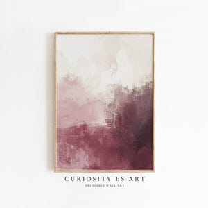 Puede incluir: Impresión artística abstracta en un marco de madera. La obra presenta una mezcla de colores, incluyendo blanco, beige y tonos de rosa y burdeos. El texto "CURIOSITY ES ART PRINTABLE WALL ART" está impreso en la parte inferior.