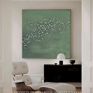 Puede incluir: Una gran obra de arte en lienzo cuadrado con un fondo verde apagado. Una bandada de pájaros blancos se representa en vuelo sobre el lienzo. El texto "CURIOSITY ES ART | HIGH QUALITY CANVAS" está en la parte inferior.