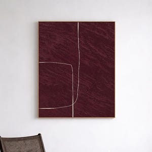 Puede incluir: Arte abstracto en lienzo burdeos con marco dorado. La obra presenta un fondo texturizado con un diseño lineal blanco. El texto "CURIOSITY ES ART | HIGH QUALITY CANVAS" está en la parte inferior. El arte está sobre una silla y una mesa auxiliar de madera oscura.